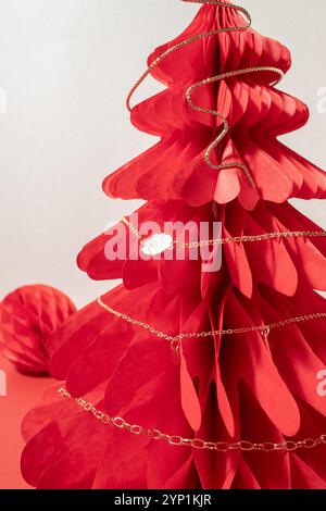 Collana di canapa dorata su un albero a nido d'ape di Natale di carta rossa. Foto Stock