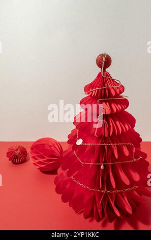 Collana di canapa dorata su un albero a nido d'ape di Natale di carta rossa. Foto Stock