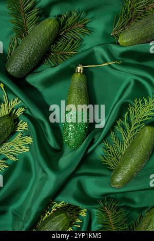 Decorazioni natalizie con rami di cetriolo e sempreverdi su sfondo di seta verde. Foto Stock