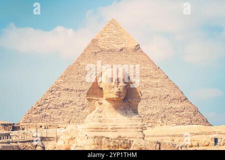 Primo piano della faccia della Grande Sfinge con piramide sullo sfondo su una bella giornata cielo blu nuvoloso a Giza, Cairo, Egitto. Vista frontale Foto Stock