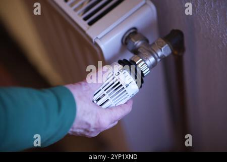 Eine Frauenhand dreht an einem Thermostatkopf an einem Heizkörper Heizkörper. Der Thermostatkopf steht auf Stufe 3. Symbolbild zum Thema Energiekosten am 28.11.2024 in Siegen/Deutschland *** Una mano di donne gira una testa termostatica su un radiatore la testa termostatica è impostata al livello 3 immagine simbolica sul tema dei costi energetici al 28 11 2024 a Siegen Germania Foto Stock