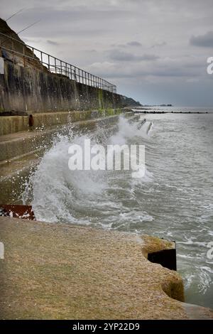 onde e spruzzi fuori dal muro marino overstrand nord norfolk inghilterra Foto Stock