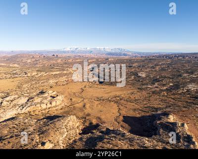 Vista aerea ad alta angolazione di un paesaggio di canyon desertico accidentato che si estende verso le montagne innevate di La Sal sotto un cielo blu terso, Utah Foto Stock