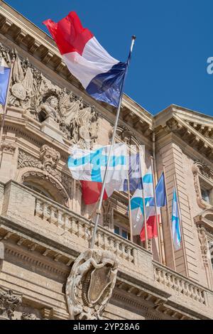 Marsiglia. Francia - 27 novembre 2024: Il municipio di Marsiglia è raffigurato con bandiere francesi che sventolano, evidenziando gli intricati dettagli architettonici e. Foto Stock