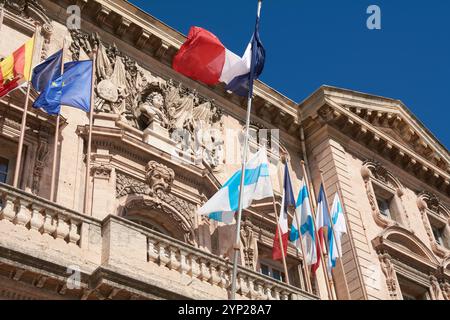 Marsiglia. Francia - 27 novembre 2024: Il municipio di Marsiglia, decorato con bandiere francesi, presenta la sua facciata storica e il cielo azzurro, perfetto per Foto Stock