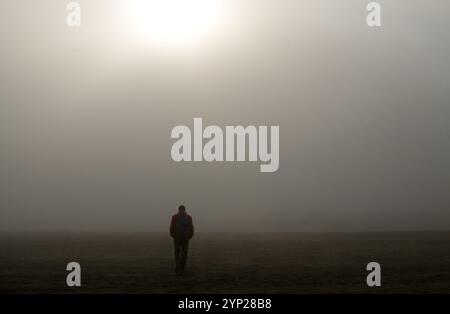 Escursionista cammina da sola in un mare di sabbia nella nebbia Foto Stock