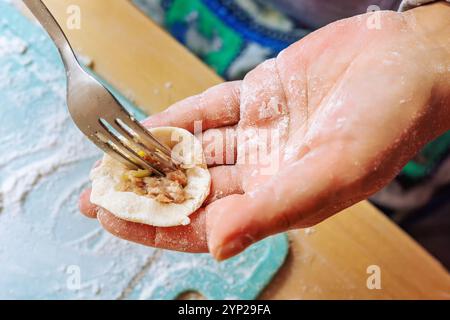A mano con l'impasto e mettendo la carne macinata con una forchetta, preparando gnocchi. Foto Stock