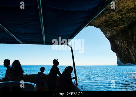 Sagome delle persone che fanno il tour in barca intorno alla famosa grotta marina della Grotta Azzurra sul litorale di Malta Foto Stock