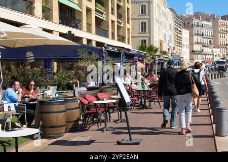 Marsiglia. Francia - 27 novembre 2024: Un affollato caffè all'aperto nel cuore di Marsiglia, con i clienti che gusteranno i loro pasti e le loro bevande all'ombra Foto Stock