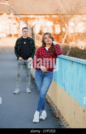 Giovane coppia che si gode una giornata di sole mentre posa casualmente su un ponte colorato. Foto Stock