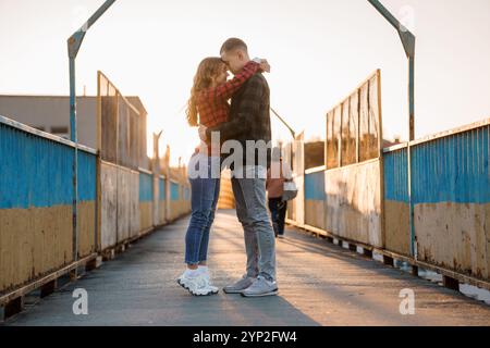 Coppia romantica che abbraccia un ponte illuminato al tramonto. Foto Stock