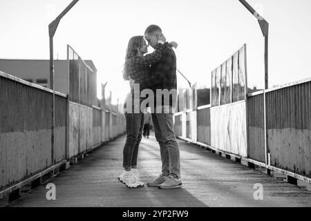 Romantico abbraccio di una coppia felice su un ponte al tramonto. Foto Stock