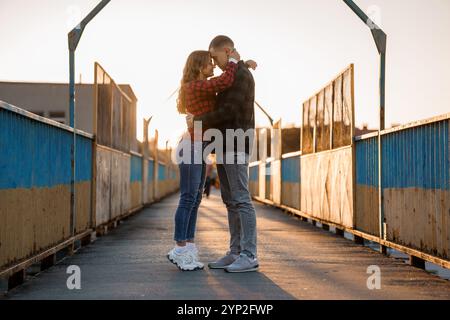 Coppia romantica che abbraccia il tramonto su un ponte. Foto Stock