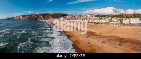 Vista panoramica aerea con droni sulla costa di Nazare, con splendida spiaggia, vivace molo roccioso e da surf, Nazare, Oeste, Estremadura, Portogallo, Europa Foto Stock