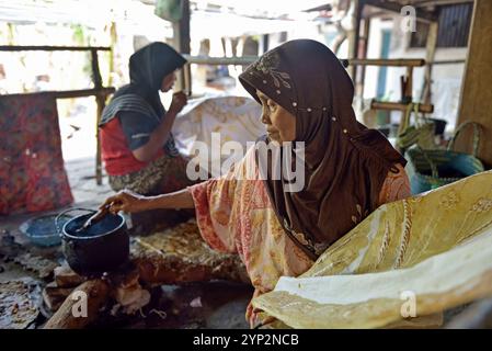 Donne che utilizzano uno strumento simile a una penna (cantando) per applicare cera calda liquida per creare un motivo sul tessuto senza disegni preliminari, Nyah Kiok batik House, cra Foto Stock