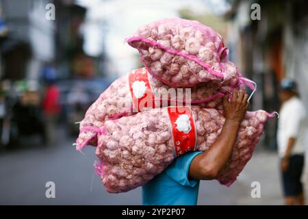 Lavoratore quotidiano al mercato alimentare tradizionale, uomo che trasporta borse pesanti con aglio sulla testa, Surabaya, Giava, Indonesia, Sud-est asiatico, Asia Foto Stock