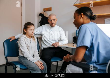 Padre serio e figlia seduti e discutere con il medico donna in sala esame medico Foto Stock