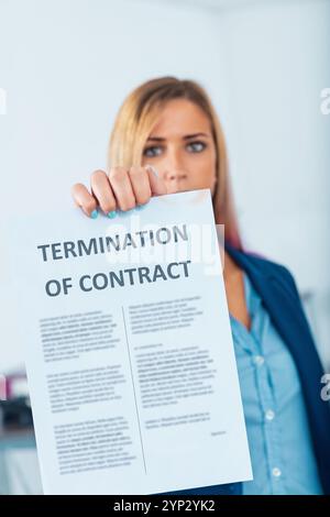 Giovane donna d'affari in un ufficio, sconvolta e frustrata, ha un avviso di licenziamento, sentendosi stressata e delusa per il suo lavoro Foto Stock
