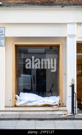 Un senzatetto che dorme bruscamente a temperature gelide, porta di accesso ad una proprietà in dover Street, Mayfair, Londra, Regno Unito, 28 novembre 2024 Foto Stock