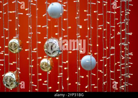 Palle di alberi di Natale e ghirlande appese su sfondo rosso. Foto Stock