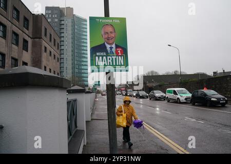 Una persona passa accanto a un manifesto elettorale per Tanaiste e Fianna Fail leader Micheal Martin nel centro di Cork, in vista delle elezioni generali di venerdì. Data foto: Giovedì 28 novembre 2024. Foto Stock