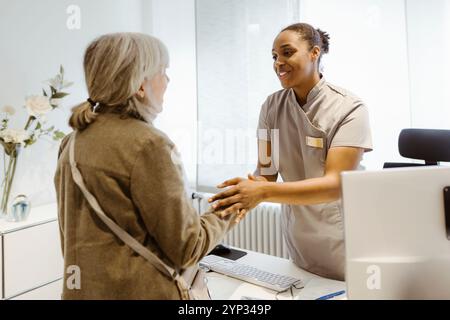 Medico sorridente che stringe la mano a un paziente anziano in clinica Foto Stock
