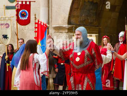 Partecipanti alle feste El Cid con costumi medievali che ballano di fronte all'Arco di Santa Maria, alle porte della città di Burgos Castiglia e León Spagna Europa Foto Stock