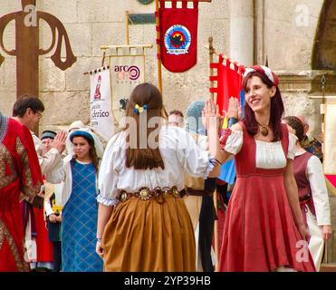 Partecipanti alle feste El Cid con costumi medievali che ballano di fronte all'Arco di Santa Maria, alle porte della città di Burgos Castiglia e León Spagna Europa Foto Stock