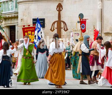 Partecipanti alle feste El Cid con costumi medievali che ballano di fronte all'Arco di Santa Maria, alle porte della città di Burgos Castiglia e León Spagna Europa Foto Stock