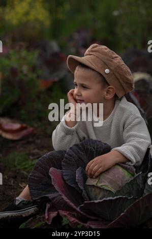 il bambino è seduto in un cavolo con cappello Foto Stock