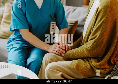 Medico che si tiene per mano con una persona anziana durante una consultazione, offrendo comfort e supporto nell'impostazione della cura Foto Stock
