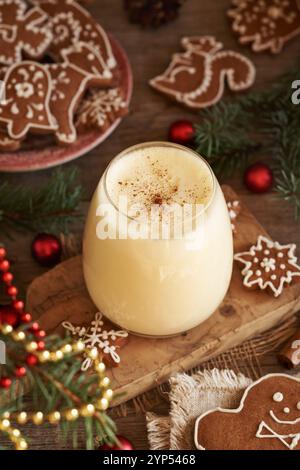 Un bicchiere di eggnog con biscotti al pan di zenzero e rami dell'albero di Natale Foto Stock