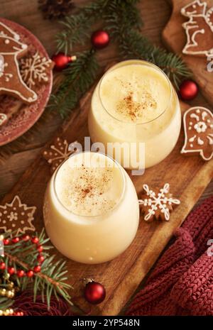 Due bicchieri di eggnog fatto in casa con biscotti natalizi di pan di zenzero e rami di abete rosso Foto Stock