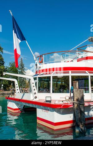 Bandiera francese sventolata sul retro di una barca da diporto attraccata ad Annecy, una città nell'angolo nord-ovest del lago d'Annecy, nella Francia alpina Foto Stock