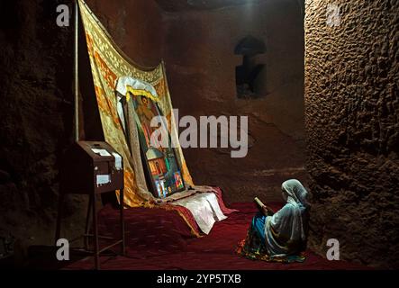 Donna ortodossa etiope che prega all'interno della chiesa scavata nella roccia di Biete Gabriel-Rufael, sito patrimonio dell'umanità dell'UNESCO Lalibela, Etiopia Foto Stock