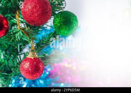 Una vista ravvicinata di un albero di Natale splendidamente decorato adornato con vivaci ornamenti rossi e verdi scintillanti, adagiato su un colorato sfondo bokeh Foto Stock