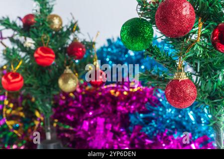 Una vista ravvicinata di un albero di Natale splendidamente decorato adornato con vivaci ornamenti rossi e verdi scintillanti, adagiato su un colorato sfondo bokeh Foto Stock