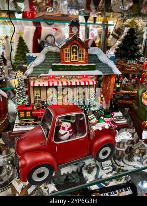 Questa foto orizzontale cattura una deliziosa mostra di decorazioni natalizie a tema invernale. Il pezzo centrale è un camion rosso in stile vintage, decorato con un ch Foto Stock