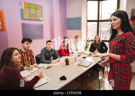 Insegnante donna che spiega il soggetto ai suoi studenti adolescenti alla scuola di lingue Foto Stock