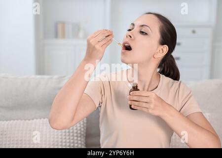 Giovane donna che prende tintura CBD all'interno. Estratto di erbe Foto Stock