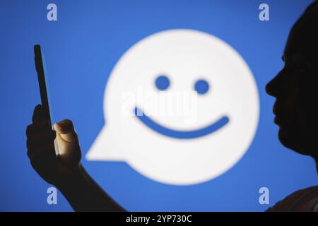 In questa foto, la silhouette di una donna contiene uno smartphone con il logo MeetMe sullo sfondo Foto Stock