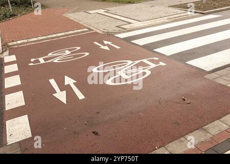 Una strada cittadina caratterizzata da una pista ciclabile e da un incrocio con marciapiedi rossi e segnaletica stradale Foto Stock