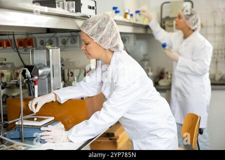 L'assistente di laboratorio femminile pesa le compresse su bilance di precisione in laboratorio biochimico Foto Stock