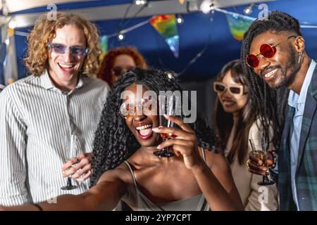 Amici multietnici chic che si divertono a fare festa di notte e si fanno selfie insieme mentre alzano i bicchieri da champagne Foto Stock