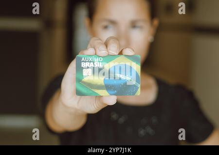In questa immagine una donna che tiene in mano la carta Auxilio Brasil (Bolsa Familia) Foto Stock