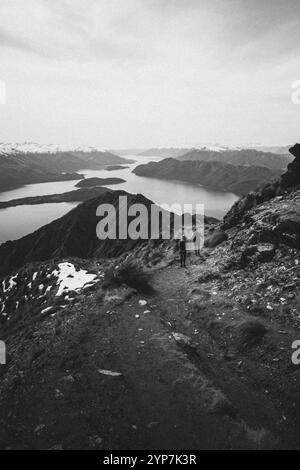 Escursione in montagna su un sentiero innevato con un'ampia vista di un lago bianco e nero, Roys Peak, Wanaka, nuova Zelanda, Oceania Foto Stock