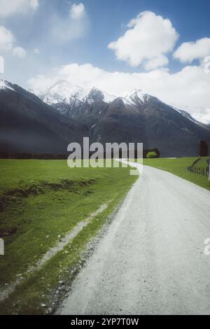 Una lunga strada conduce dritto verso montagne innevate, Cattle Flat, Wanaka, nuova Zelanda, Oceania Foto Stock