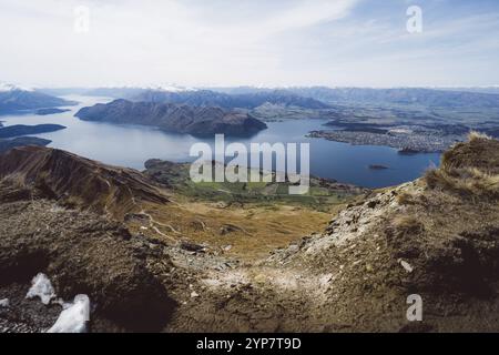 Ampio panorama di una valle con un lago esteso circondato da colline, Roys Peak, Wanaka, nuova Zelanda, Oceania Foto Stock