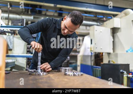 Uomo che misura pezzi di metallo utilizzando un micrometro presso la fabbrica metallurgica cnc Foto Stock