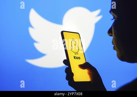 In questa immagine, la silhouette di una donna contiene uno smartphone con il logo di un'app Koo visualizzato sullo schermo e il logo Twitter visualizzato nella Foto Stock